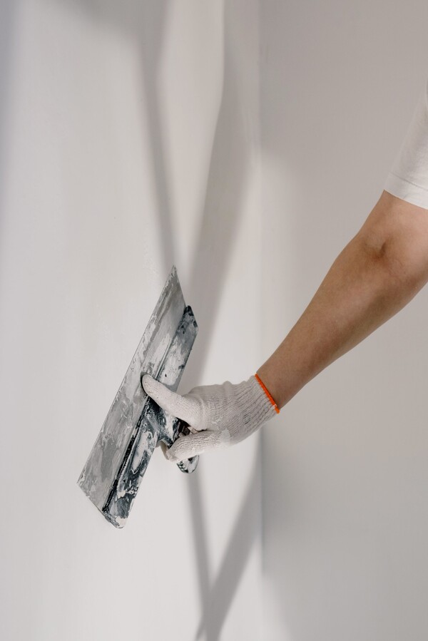 Professional plasterer applying smooth finishing coat to interior wall for a seamless and polished appearance.